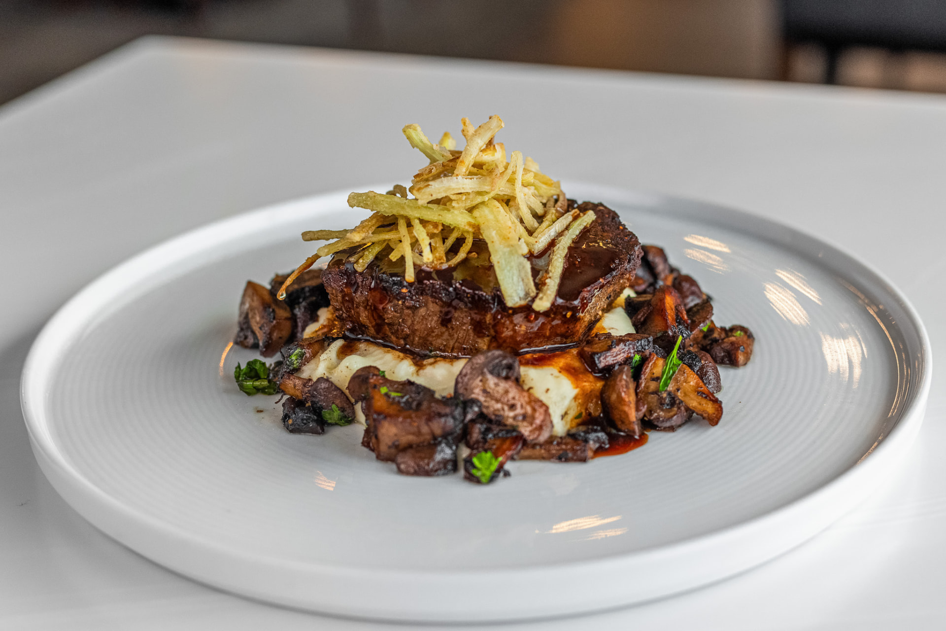 Seared beef tenderloin over mushrooms and whipped potato, topped with crisp shoestring potatoes